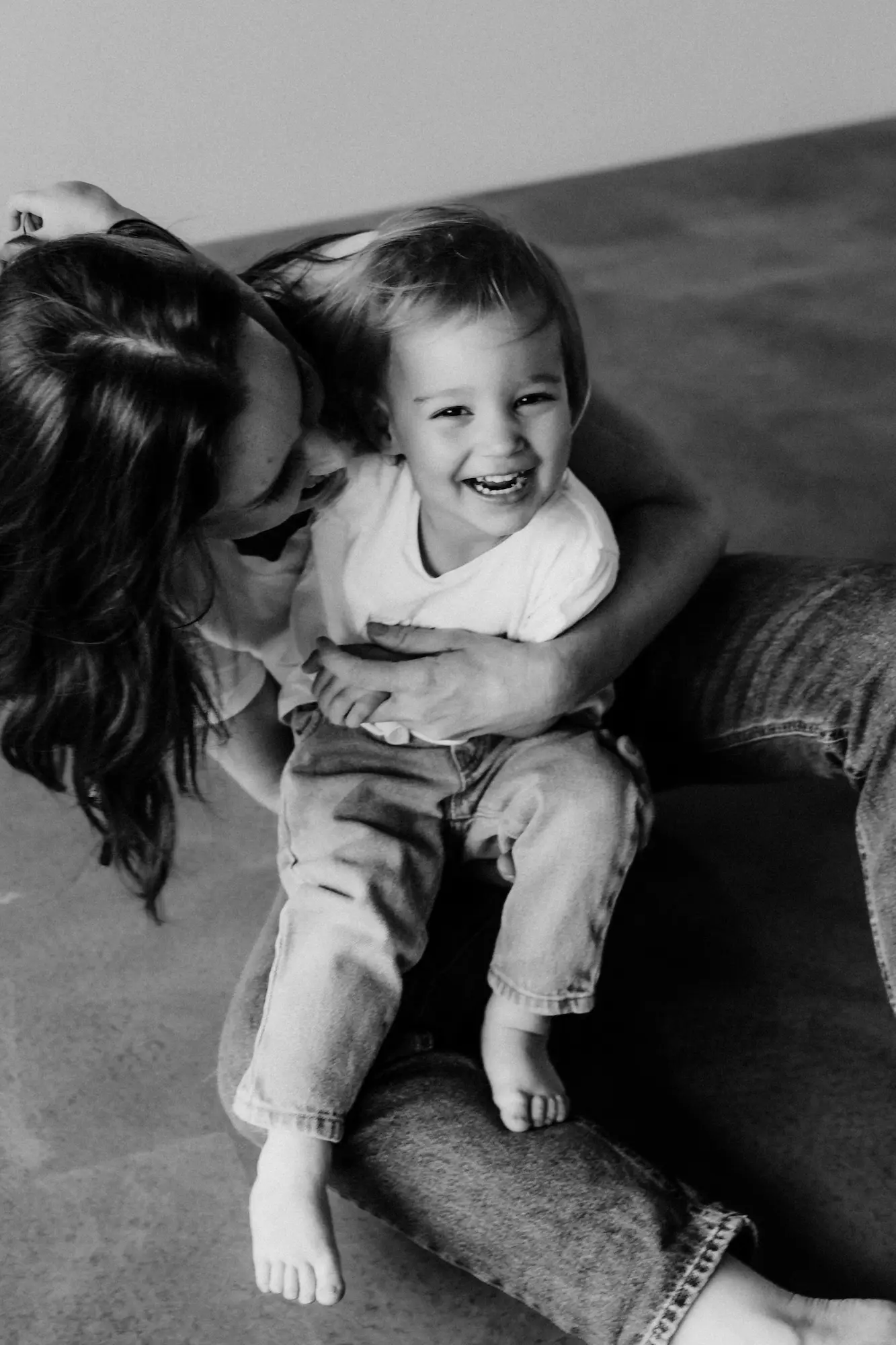 Mama sa hrá s malým smejúcim sa synom v náručí, čiernobiela fotografia