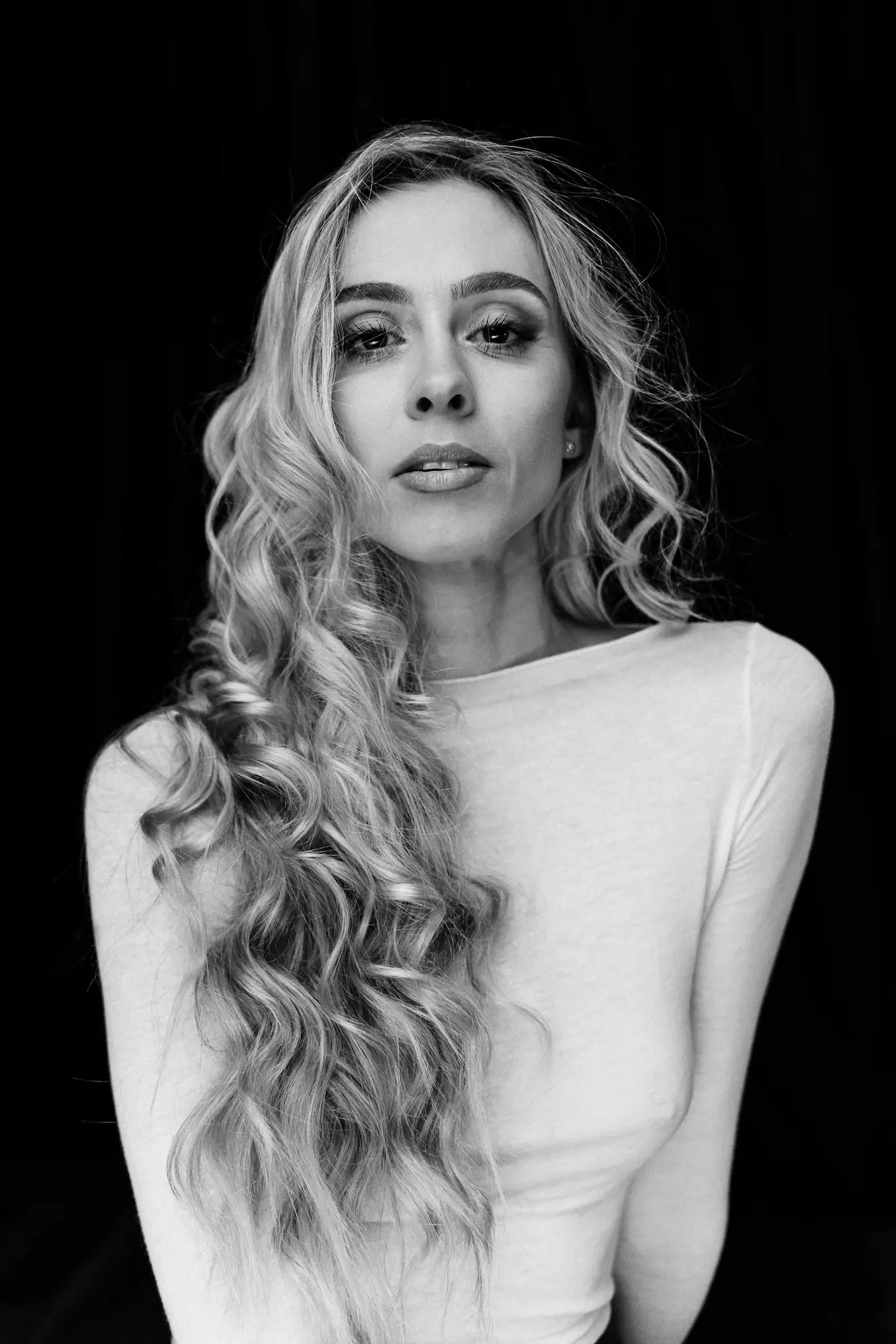 Blondínka s dlhými vlnitými vlasmi v bielom tope, čiernobiela fotografia