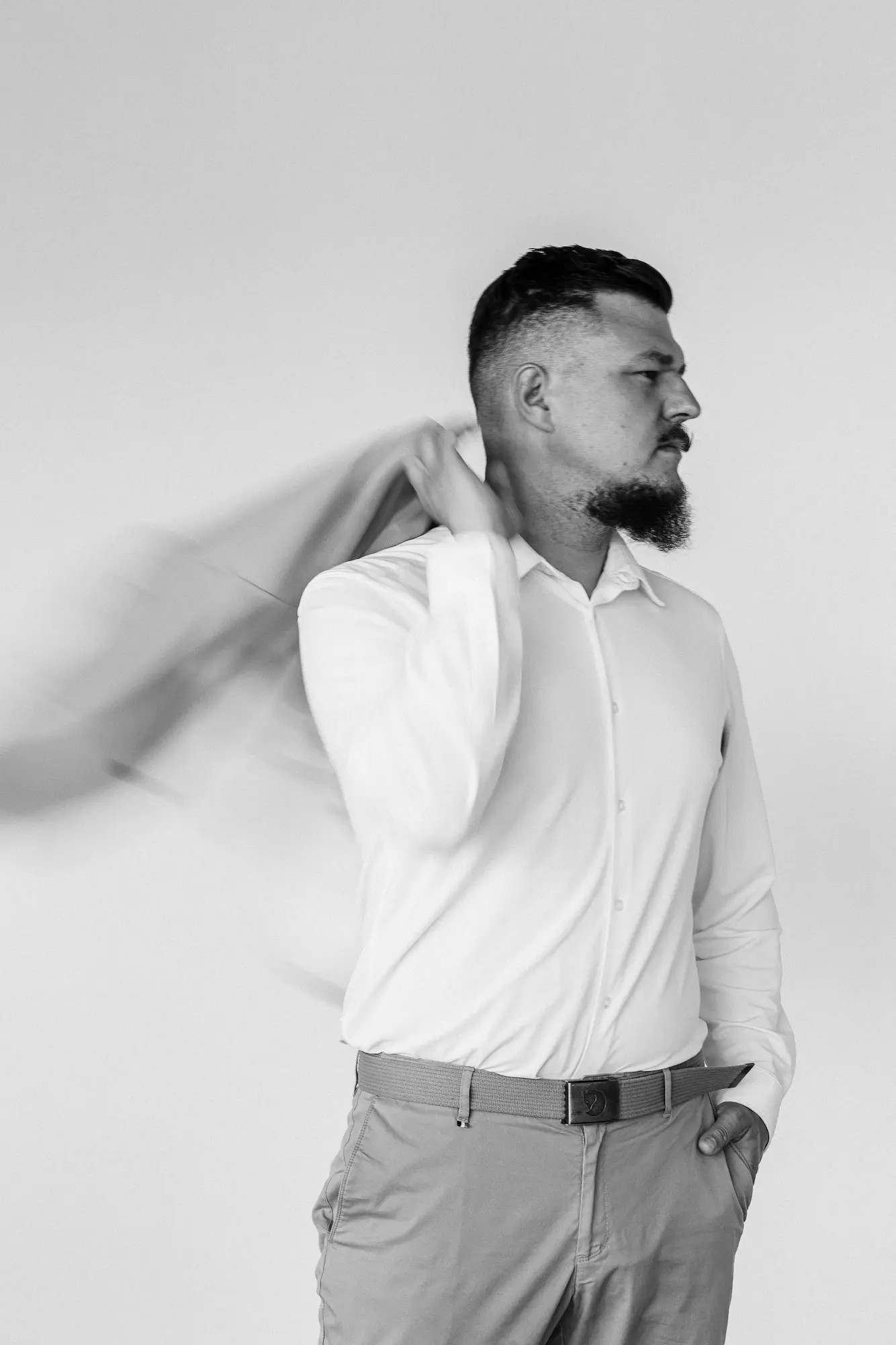 Profil muža v bielej košeli s pohybom saka v pozadí, čiernobiely branding portrét