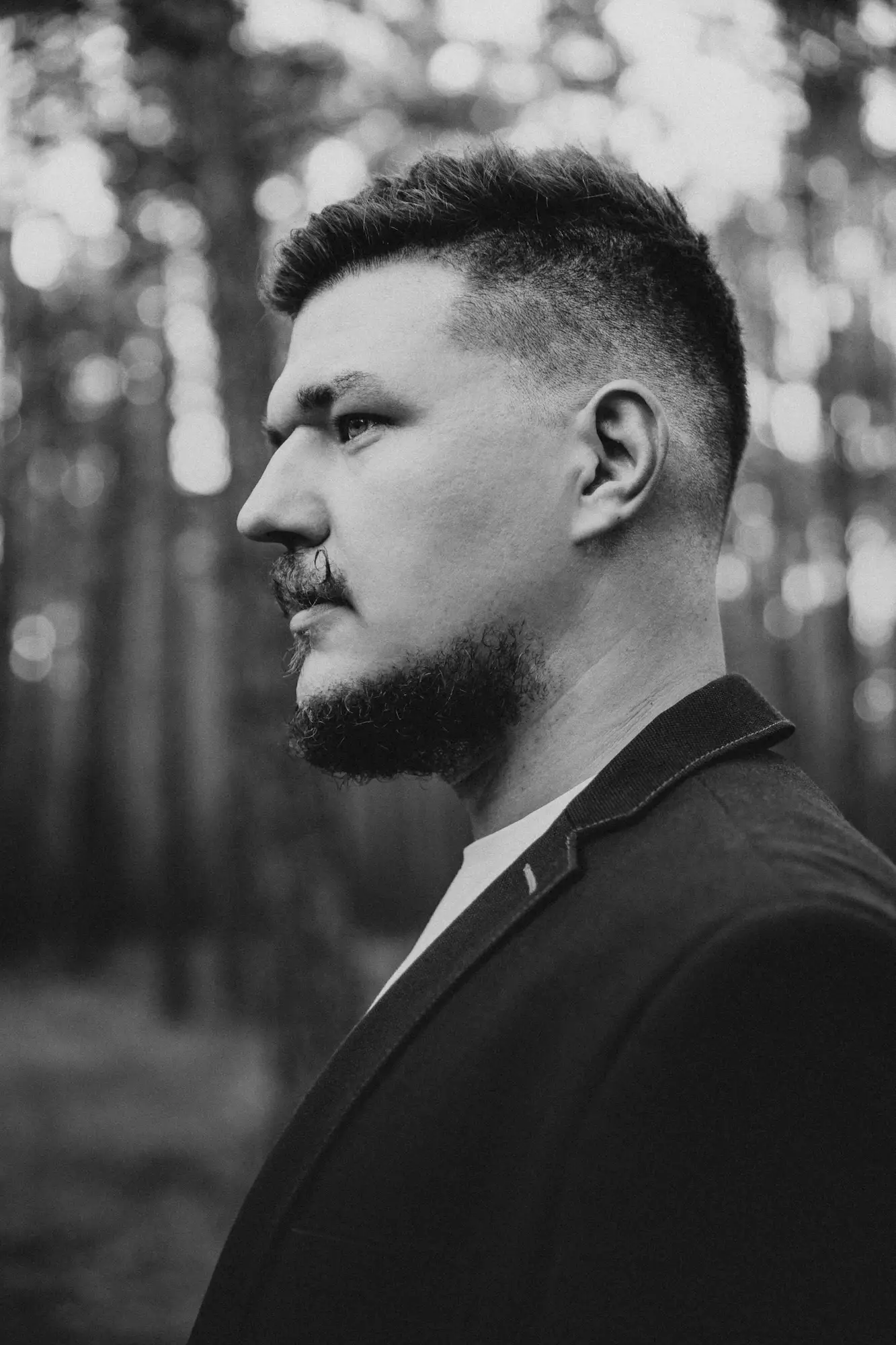 Profilový portrét muža s bradou v lese, čiernobiela fotografia