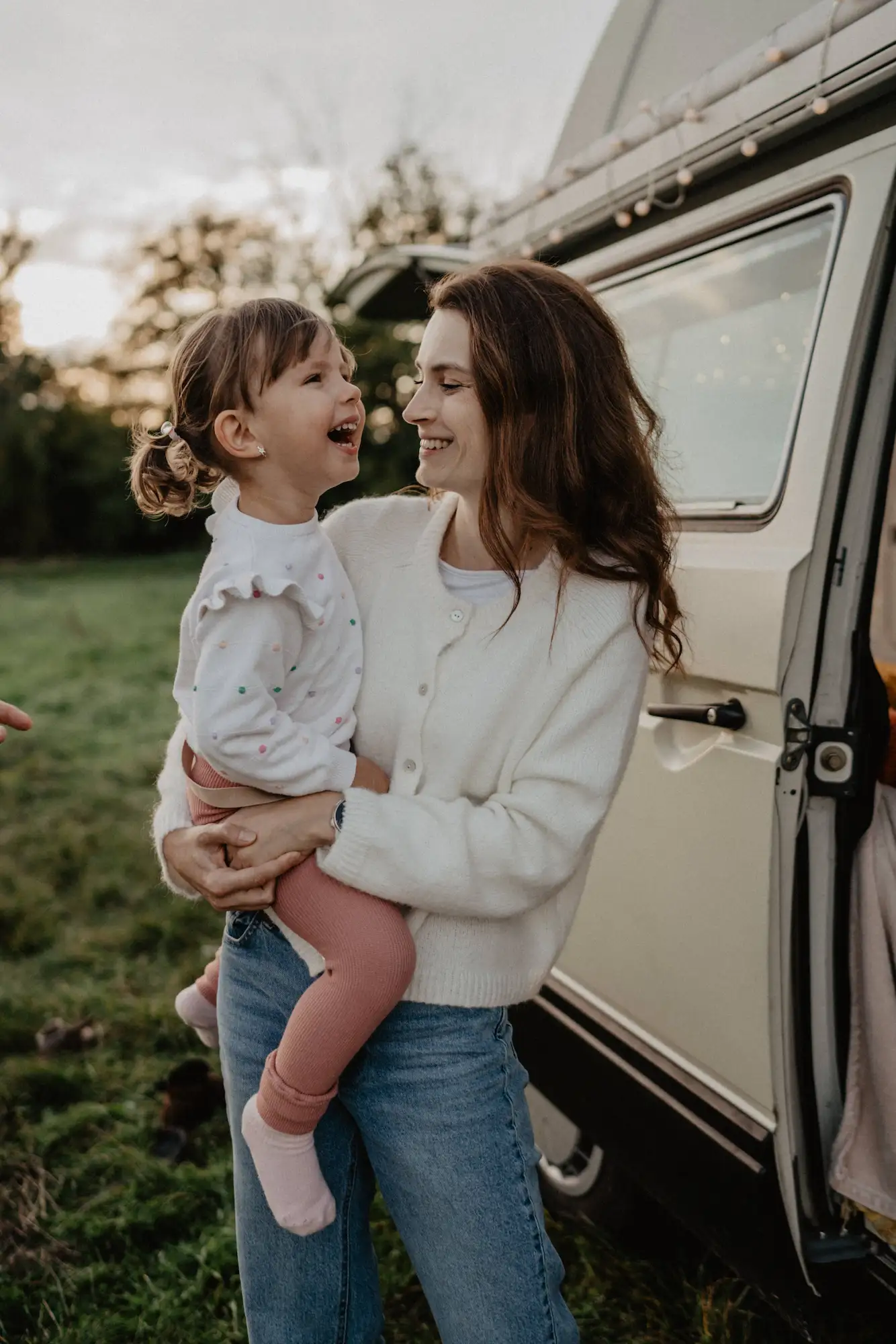 Mama s malou dcérkou v náručí pri karavane pri západe slnka